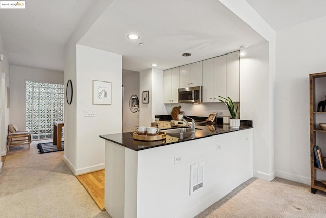 kitchen with white cabinetry, kitchen peninsula, and sink