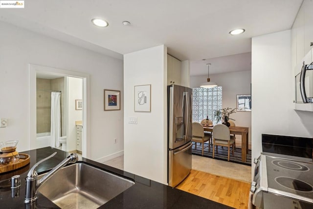 kitchen featuring sink, decorative light fixtures, light hardwood / wood-style flooring, stainless steel appliances, and white cabinets