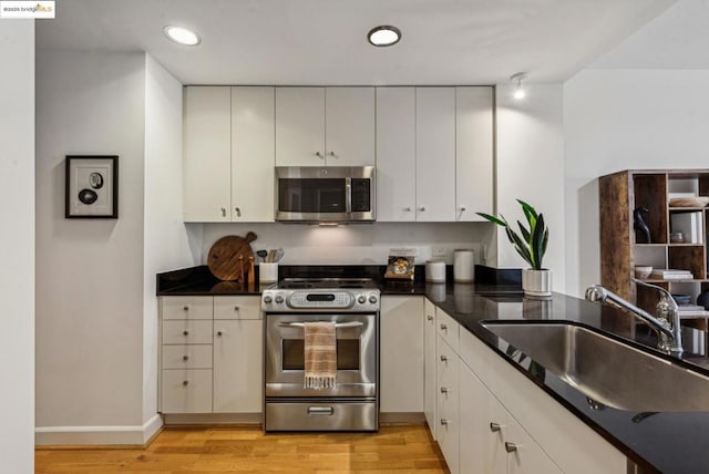 kitchen featuring white cabinetry, appliances with stainless steel finishes, sink, and light hardwood / wood-style flooring