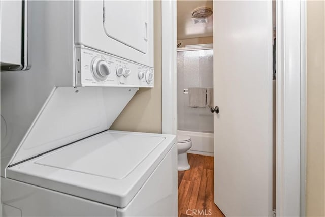 clothes washing area featuring stacked washer and dryer and hardwood / wood-style floors