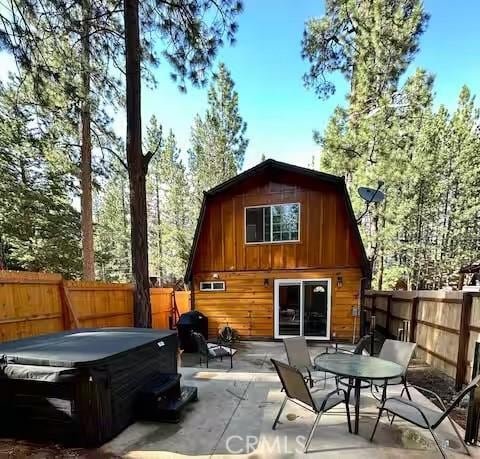 rear view of house featuring a hot tub and a patio