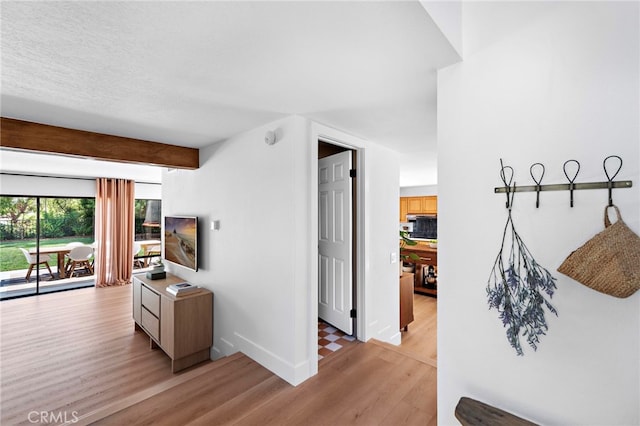 hallway with beam ceiling and light hardwood / wood-style floors