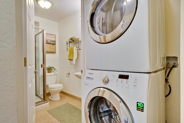 clothes washing area with light tile patterned floors and stacked washer / dryer