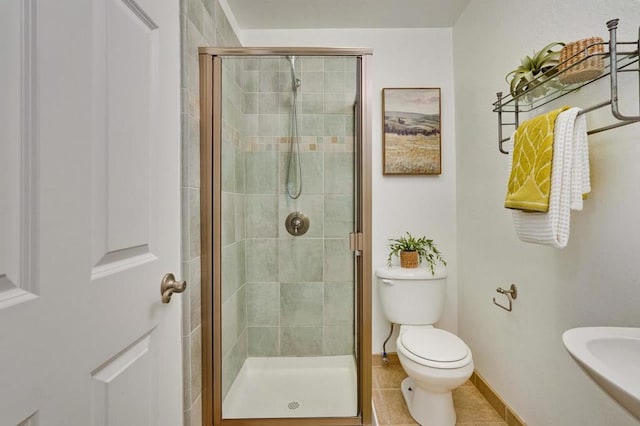 bathroom with tile patterned flooring, a shower with shower door, and toilet