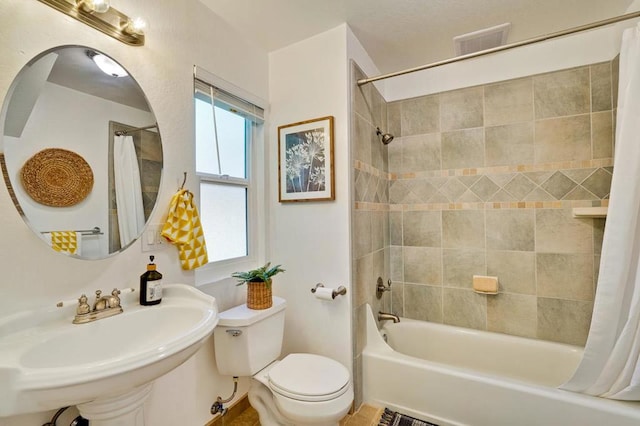 full bathroom featuring sink, shower / bath combination with curtain, and toilet