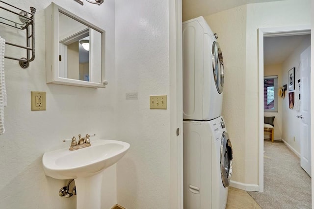 bathroom with tile patterned flooring, sink, and stacked washer / dryer