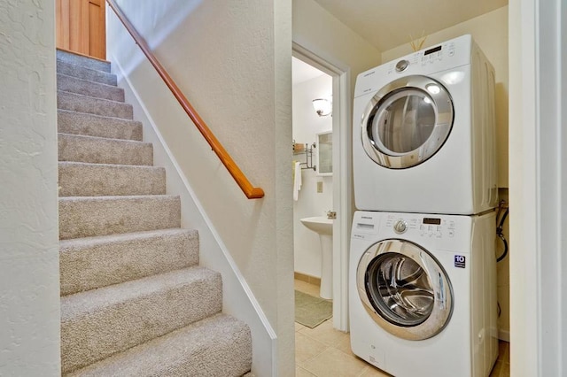 laundry area with stacked washing maching and dryer and light tile patterned floors