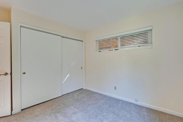 unfurnished bedroom with light carpet and a closet