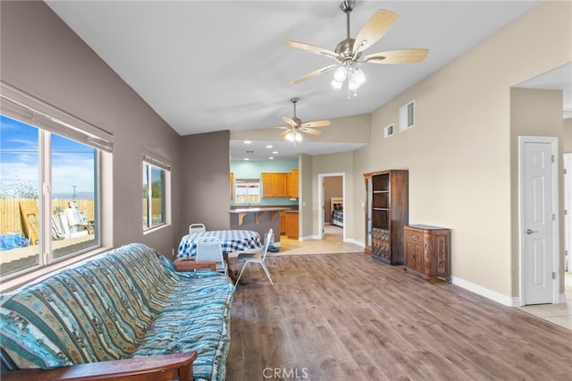 living room featuring ceiling fan, lofted ceiling, and light wood-type flooring