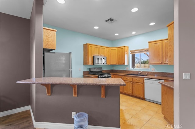 kitchen featuring appliances with stainless steel finishes, a kitchen breakfast bar, kitchen peninsula, and sink