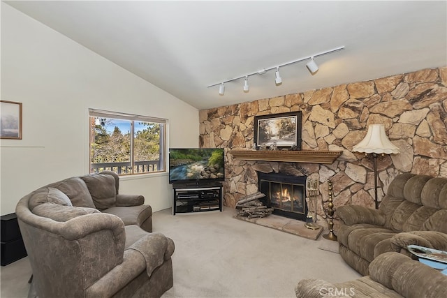 carpeted living area with vaulted ceiling, a stone fireplace, and track lighting