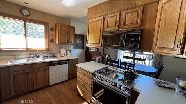 kitchen featuring black microwave, a sink, light countertops, dishwasher, and gas range