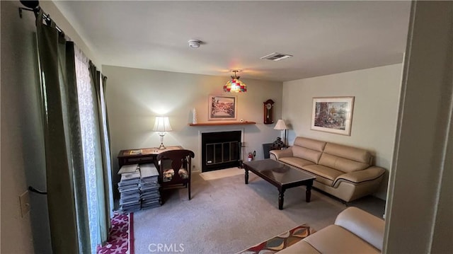 carpeted living area with a fireplace with flush hearth and visible vents