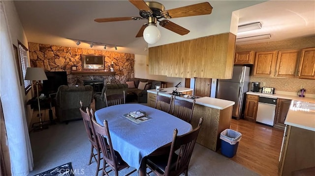 dining space with light wood finished floors, a fireplace, and a ceiling fan