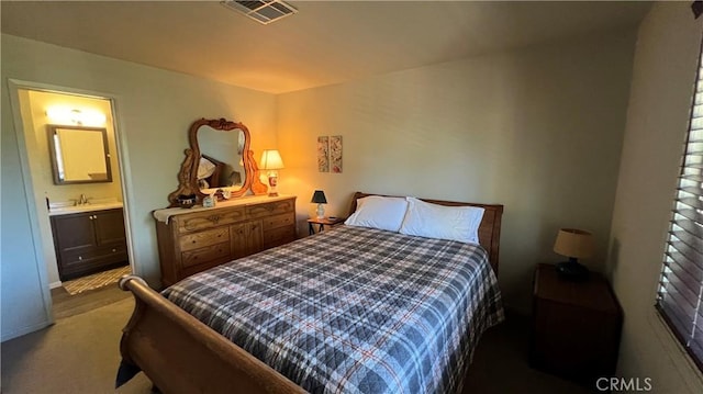 carpeted bedroom with ensuite bath, a sink, and visible vents