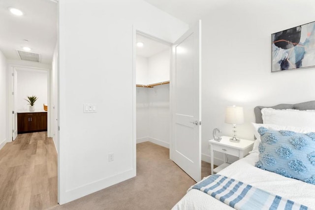 carpeted bedroom with a walk in closet and a closet