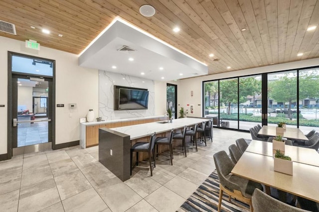 kitchen with a large island with sink, a healthy amount of sunlight, a breakfast bar area, and wood ceiling