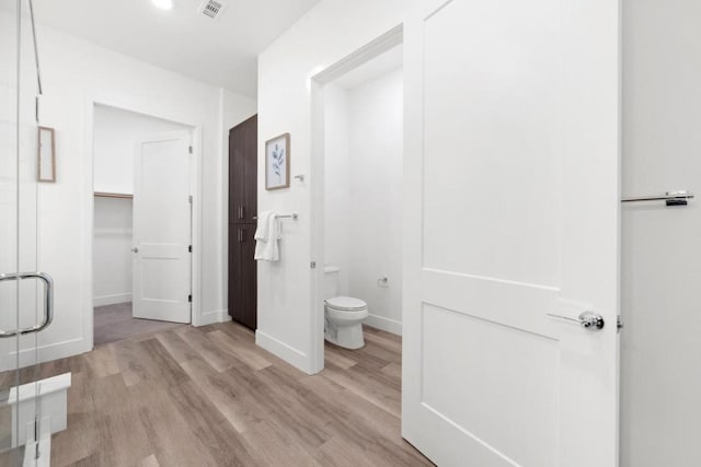 bathroom featuring hardwood / wood-style flooring, walk in shower, and toilet