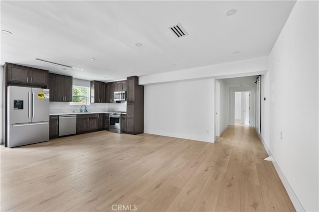 kitchen with dark brown cabinetry, light wood finished floors, visible vents, stainless steel appliances, and light countertops