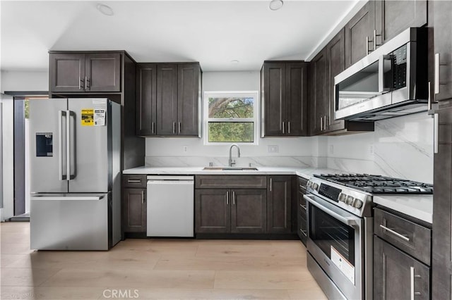 kitchen with light countertops, appliances with stainless steel finishes, light wood-type flooring, and a sink