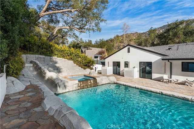 pool featuring a patio area and an in ground hot tub