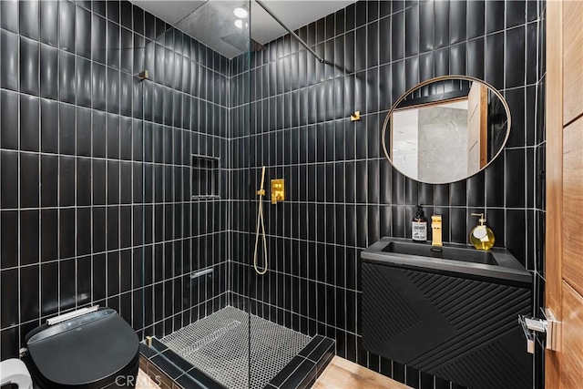 bathroom featuring toilet, a tile shower, tile walls, and a sink