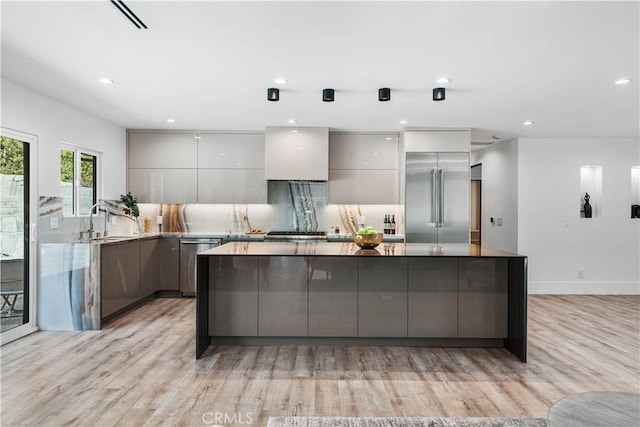 kitchen with gray cabinetry, stainless steel appliances, a sink, decorative backsplash, and modern cabinets