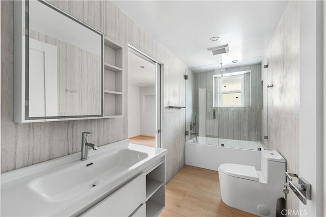 full bathroom featuring visible vents, toilet, combined bath / shower with glass door, vanity, and wood finished floors