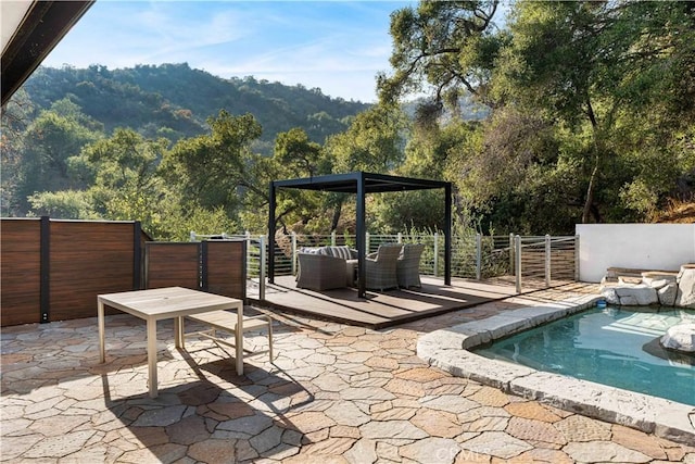 view of patio featuring a fenced in pool, fence, a forest view, and a mountain view