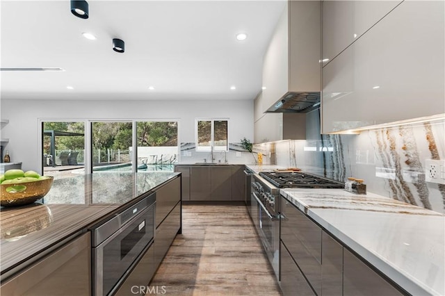 kitchen with light countertops, appliances with stainless steel finishes, light wood-type flooring, decorative backsplash, and modern cabinets