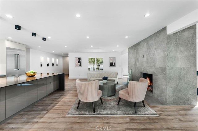 living room with light wood-type flooring, recessed lighting, a fireplace, and an accent wall