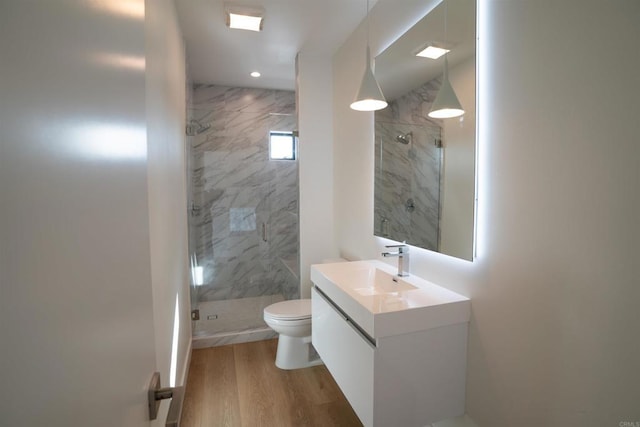 bathroom with walk in shower, hardwood / wood-style floors, vanity, and toilet