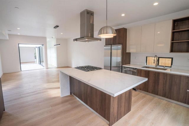 kitchen with sink, pendant lighting, island exhaust hood, stainless steel appliances, and light hardwood / wood-style floors