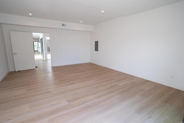 spare room featuring electric panel and light wood-type flooring