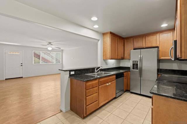 kitchen with appliances with stainless steel finishes, sink, dark stone counters, ceiling fan, and kitchen peninsula