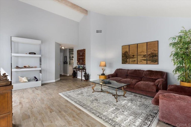 living room featuring beam ceiling, high vaulted ceiling, and light wood-type flooring