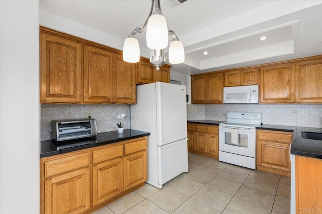 kitchen featuring pendant lighting, backsplash, light tile patterned floors, a tray ceiling, and white appliances