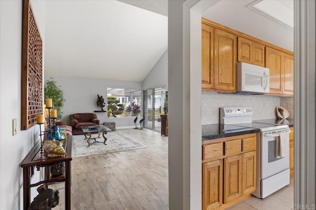 kitchen featuring tasteful backsplash, white appliances, light hardwood / wood-style flooring, and lofted ceiling