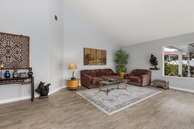 living room with high vaulted ceiling and light hardwood / wood-style flooring