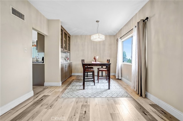 dining room with baseboards, light wood-type flooring, a notable chandelier, and visible vents