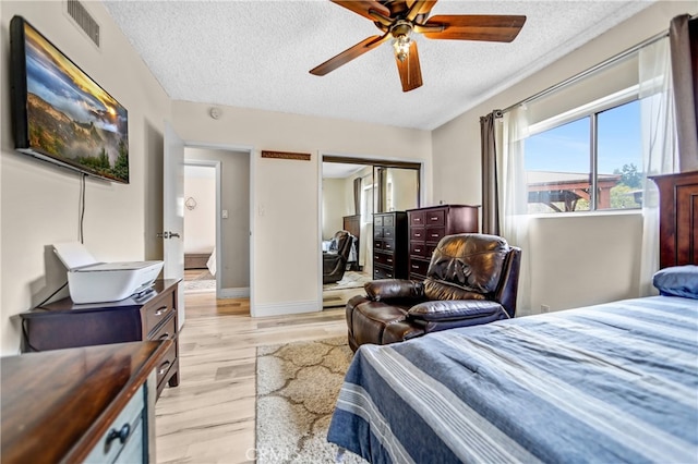 bedroom with visible vents, baseboards, a closet, light wood-type flooring, and a textured ceiling