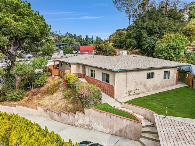 exterior space featuring stucco siding, fence, and a lawn