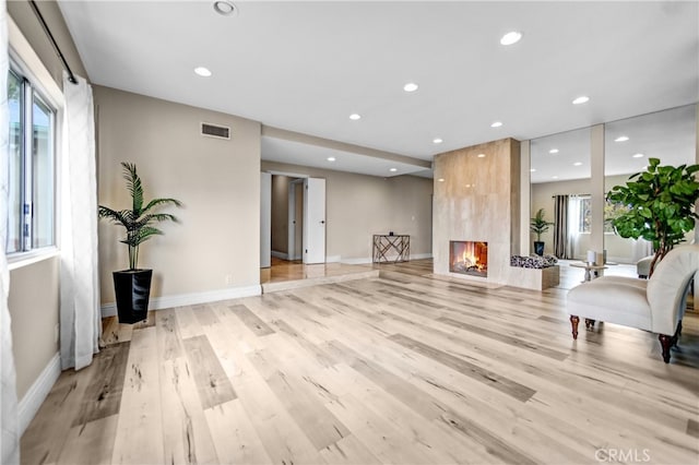 interior space with light wood-style floors, a tiled fireplace, visible vents, and recessed lighting