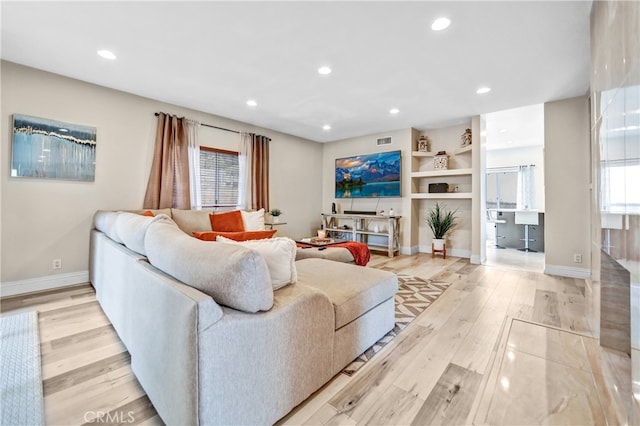 living room featuring baseboards, light wood finished floors, and recessed lighting