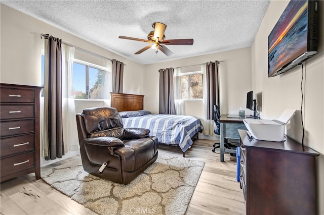 bedroom featuring a textured ceiling, multiple windows, and light wood-type flooring