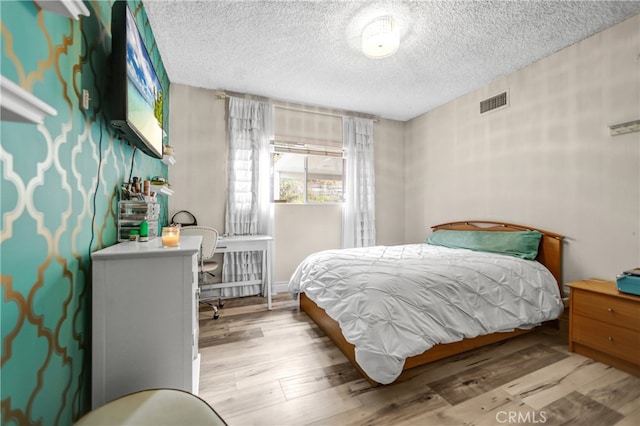 bedroom featuring a textured ceiling, wood finished floors, and visible vents