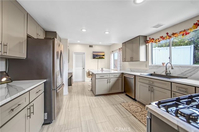 kitchen with a peninsula, gray cabinetry, visible vents, stainless steel appliances, and a sink