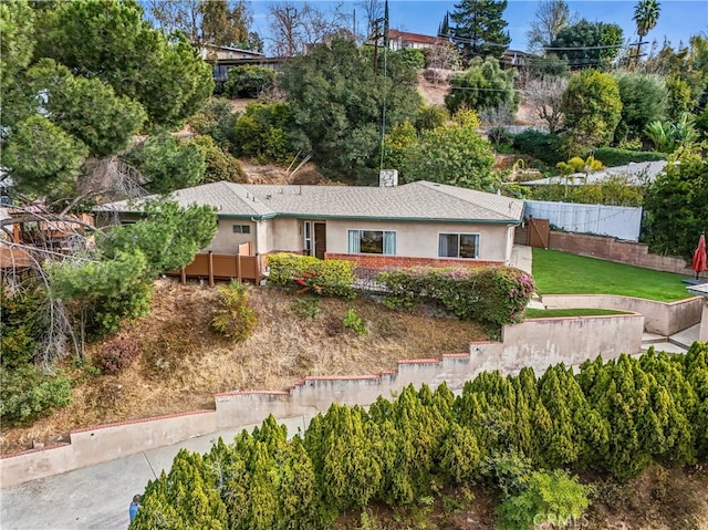 ranch-style house with a chimney, stucco siding, fence, and a front yard