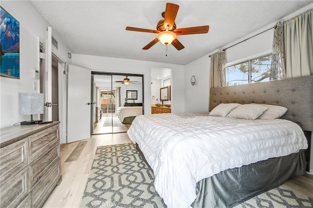 bedroom with light wood finished floors, ceiling fan, visible vents, and ensuite bath
