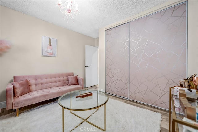 living area with a chandelier, wood finished floors, and a textured ceiling